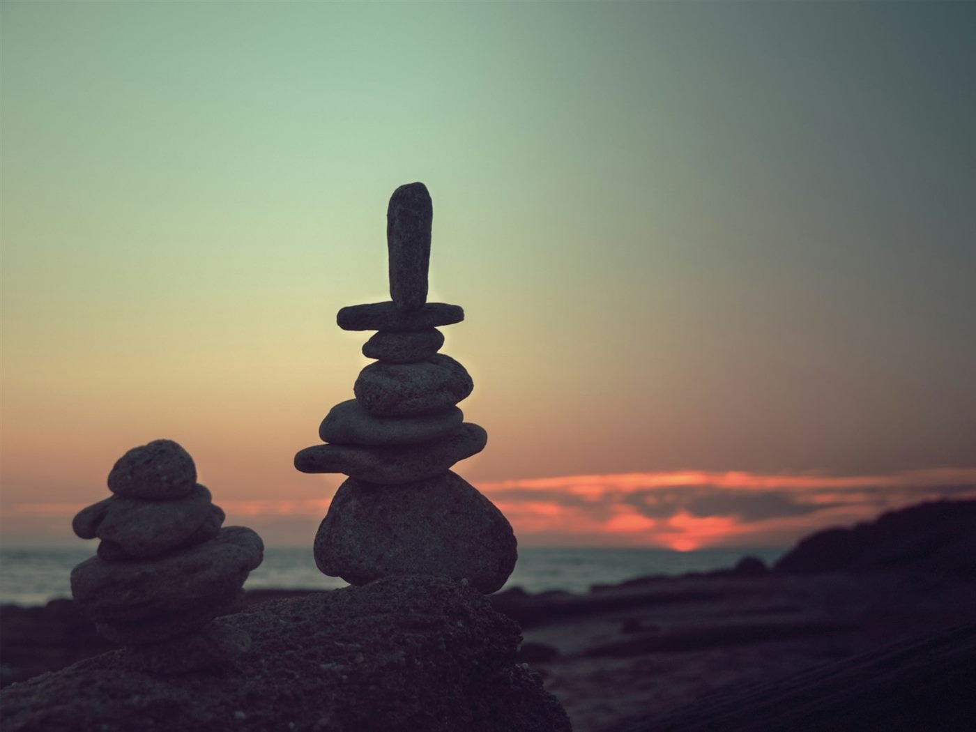 Pedras equilibradas sobre uma rocha, contra o céu de um pôr do sol